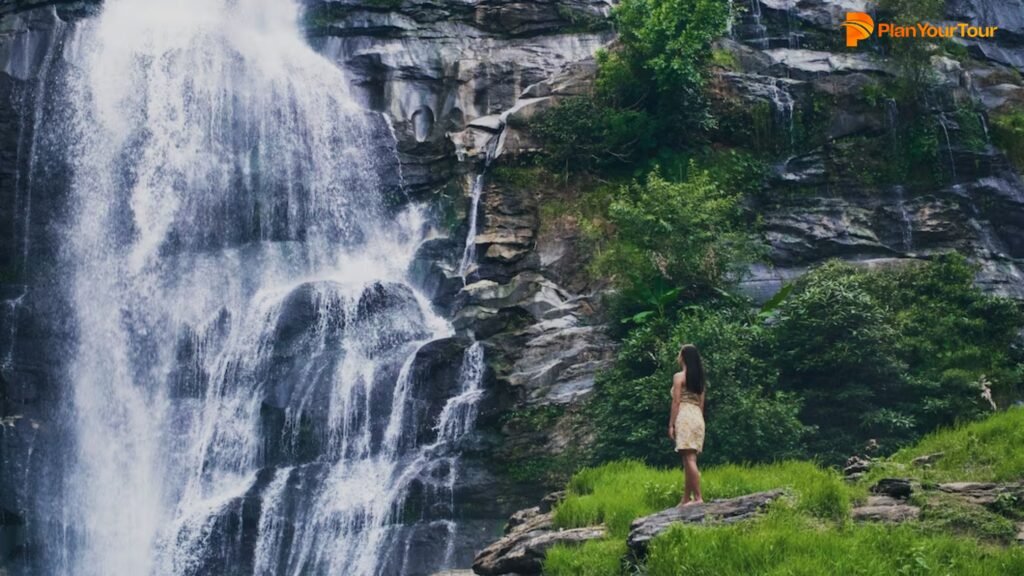 a person standing on a rock near a waterfall : Athirapally, Kerala
