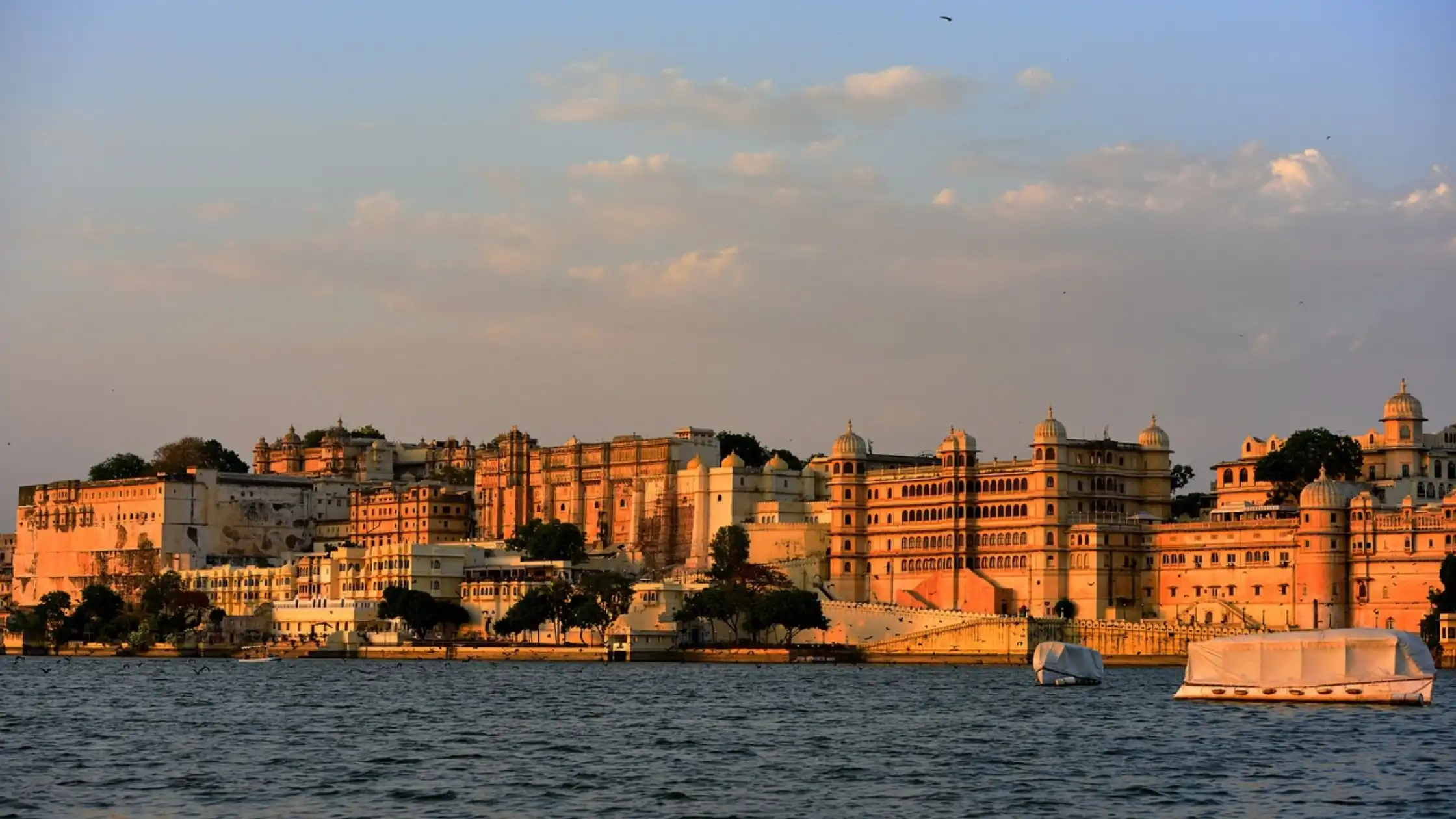 A serene landscape with a clear blue sky, and a tranquil lake reflecting the surrounding nature of City of Lakes, Udaipur