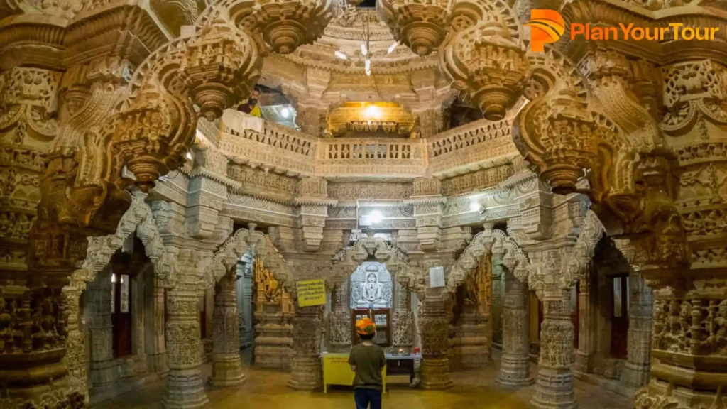 The interior of a Shantinath Temple showcasing detailed and intricate carvings on the walls and pillars, highlighting exquisite craftsmanship.