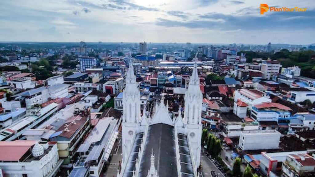 a large white building with towers and a city in the background : Thrissur , Kerala
