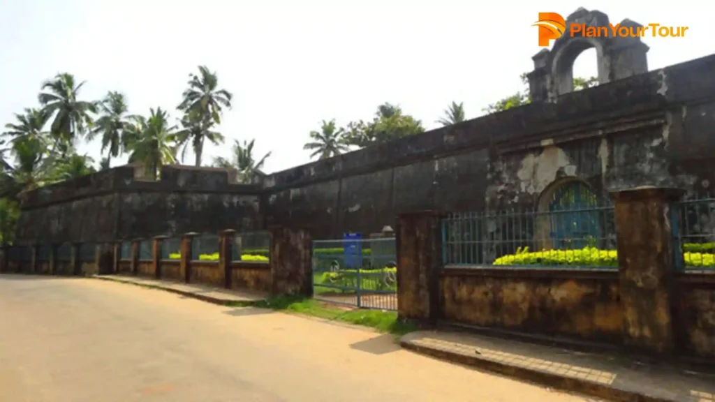 a building with a fence and trees of Anjengo Fort, historical place to visit in Varkala
