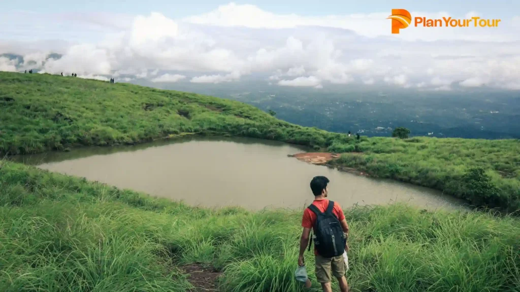 a person standing on a Chembra Peak with a body of water, popular destinations in Wayanad
