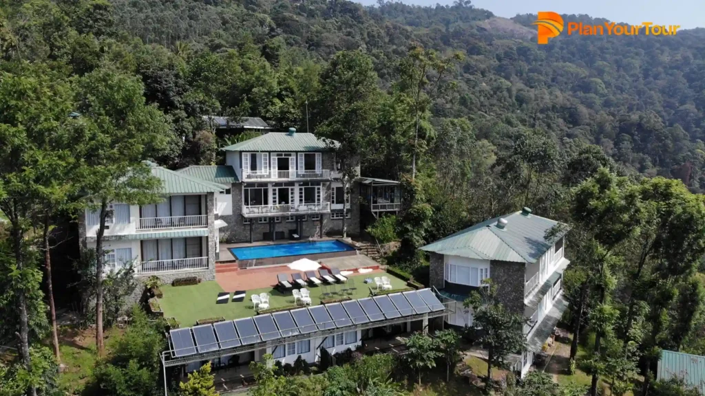 a house with a pool surrounded by trees of pice Tree Munnar, pool resorts in Munnar
