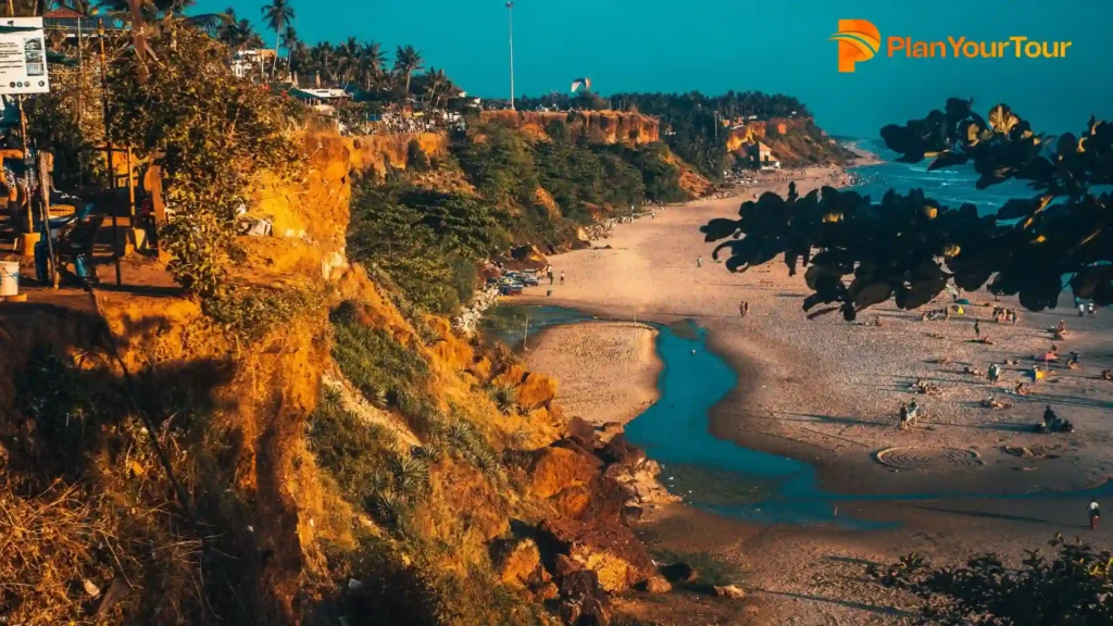 a beach with a body of water and trees of Varkala Cliff which is famous tourist attraction of Varkala
