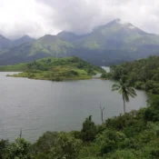 A serene lake bordered by majestic mountains and lush green trees under a clear blue sky. (1)