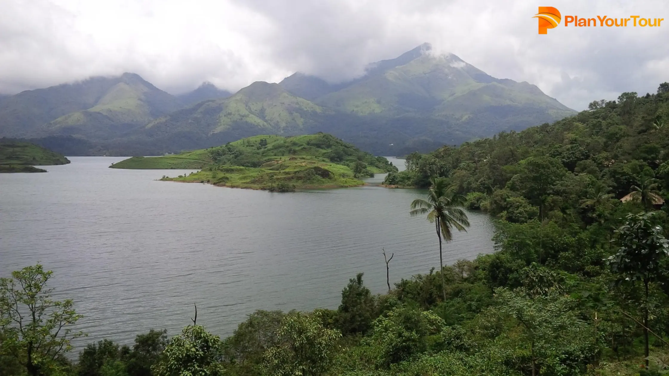 A serene lake bordered by majestic mountains and lush green trees under a clear blue sky. (1)